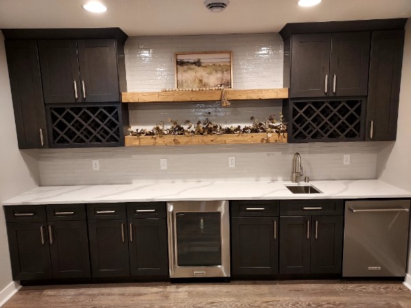 Wet bar with stacked linear tile backsplash, dark cabinets and white quartz counters