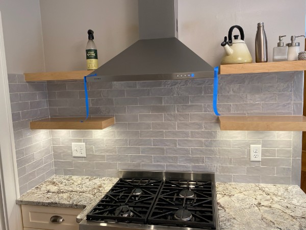 Grey subway tile backsplash with range hood