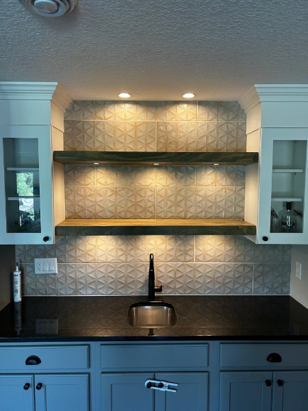 Dimensional white 3D faceted tile backsplash behind floating wood shelves and bar sink